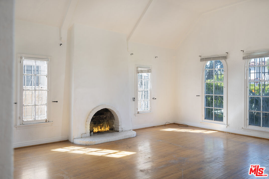 The vaulted-ceiling great room with lit stone fireplace and arched leaded windows at 424 N Edinburgh Ave