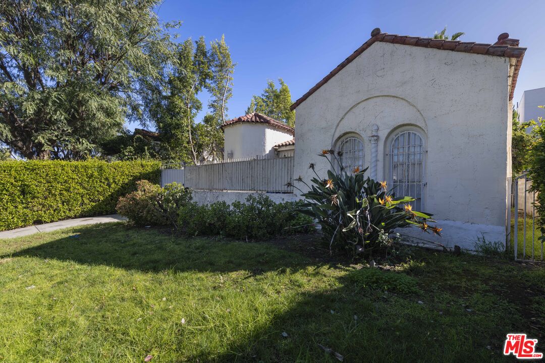 The Spanish Colonial facade at 424 N Edinburgh Ave, with arched leaded windows and a clay tile roofline behind a hedge.