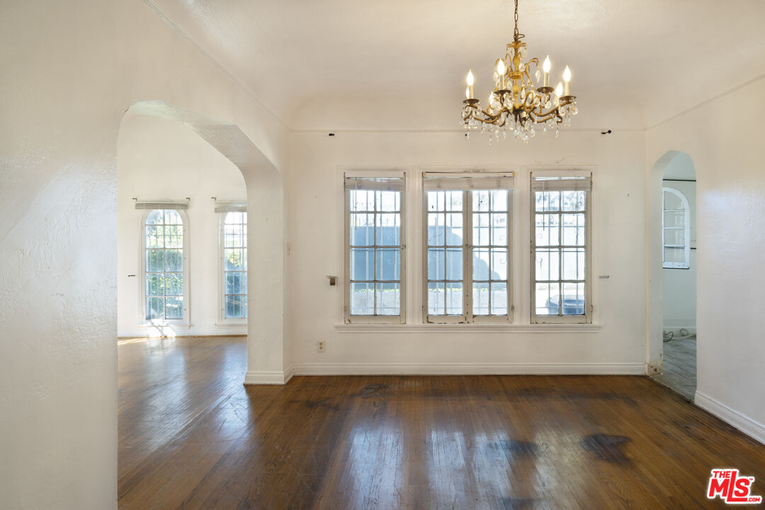 The dining room with a brass chandelier, original arched windows, and dark hardwood floors.