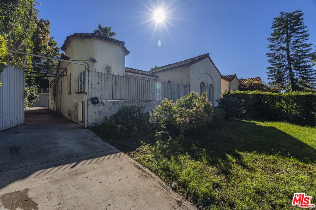 The side approach to the property, low-walled, with the Spanish facade rising behind.